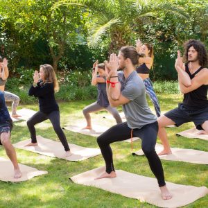 Yoga lovers enjoying practice on grass. Man and woman doing yoga outdoors, standing on mats and holding asana. Training body concept